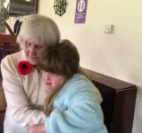 An older woman and younger woman sharing a warm hug at a community event