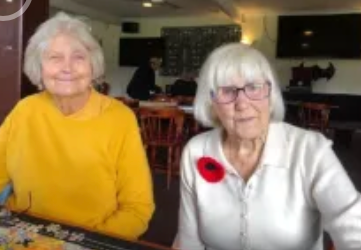 Two older women smiling together at a community gathering