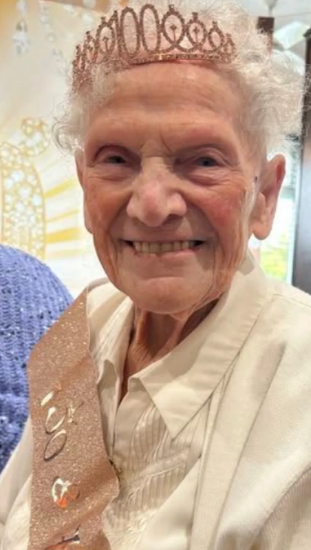Elderly community member wearing a tiara and sash at a celebration