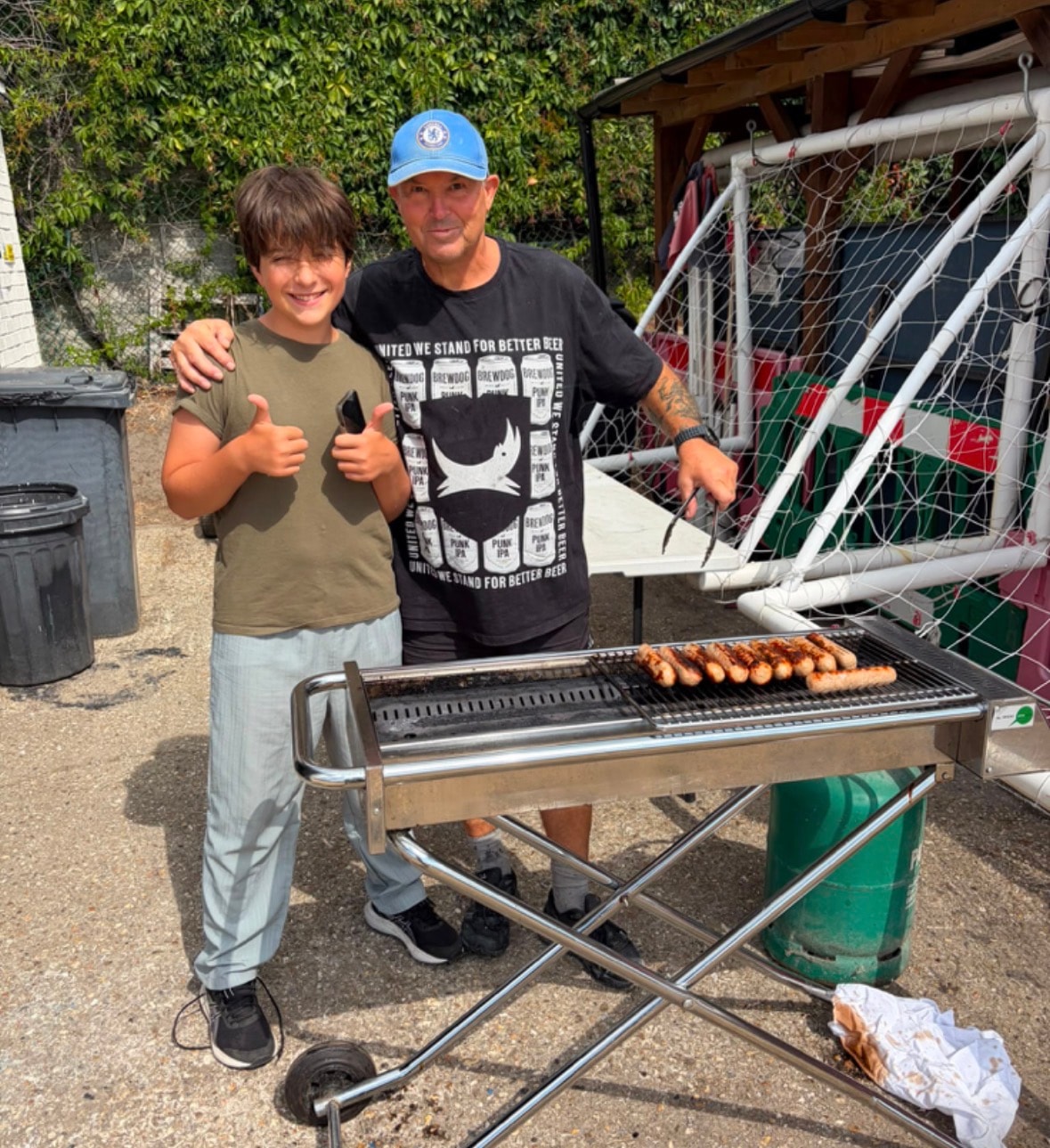 Man and boy cooking sausages together on a BBQ at a Healing Hubs summer event