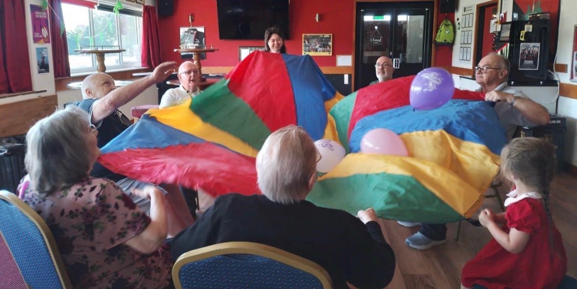 Joyful group parachute game with hands raised